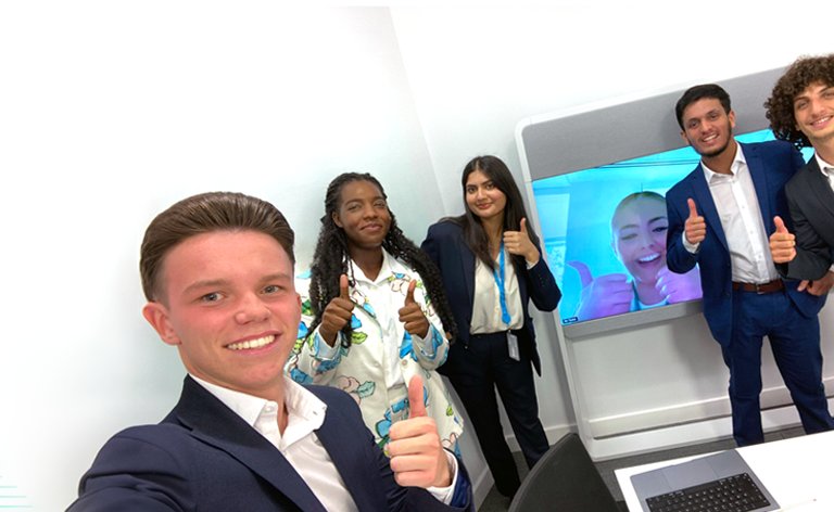 Four people huddled together smiling. One holds a Cisco umbrella.