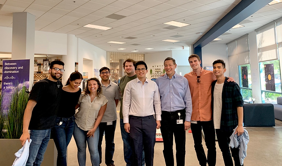 Group of nine people stand together smiling.