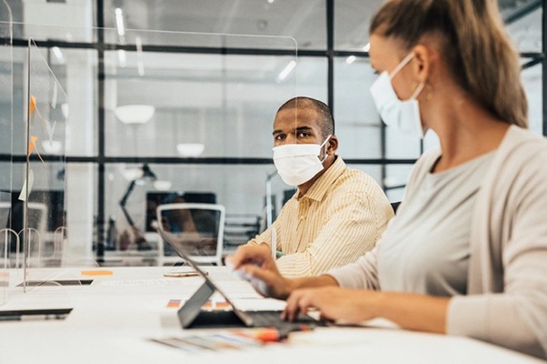 Man and woman wearing PPE in workspace