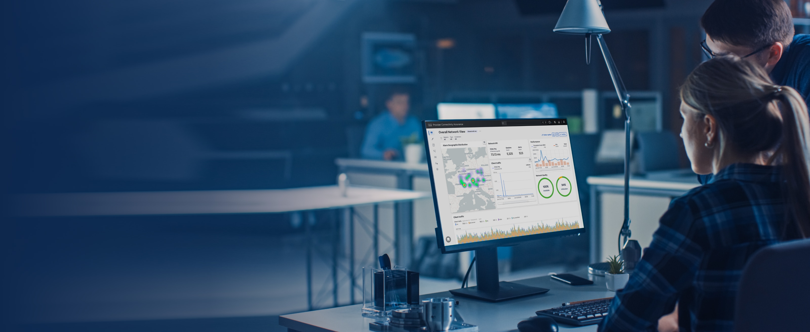 Two workers at a desk reviewing a Provider Connectivity Assurance dashboard