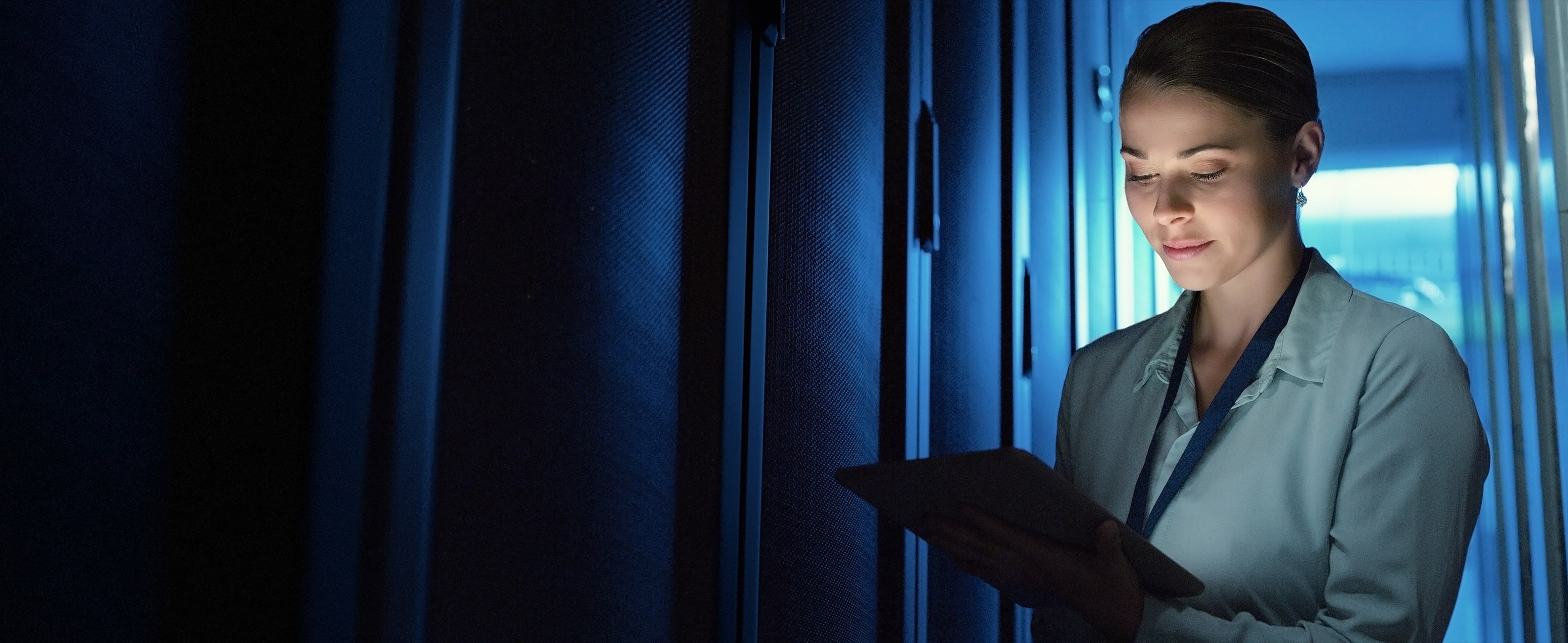 IT worker using a tablet while monitoring equipment in an enterprise server room.