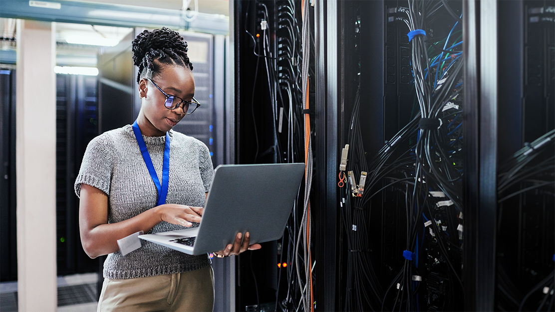 IT worker checking network performance on a laptop in a server room