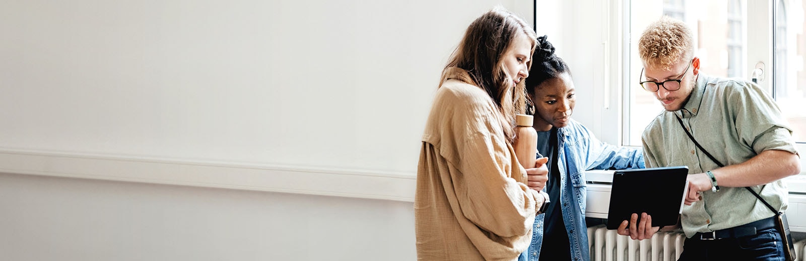 Workers in an office huddled around a tablet while one worker shares findings from an FSO Platform dashboard